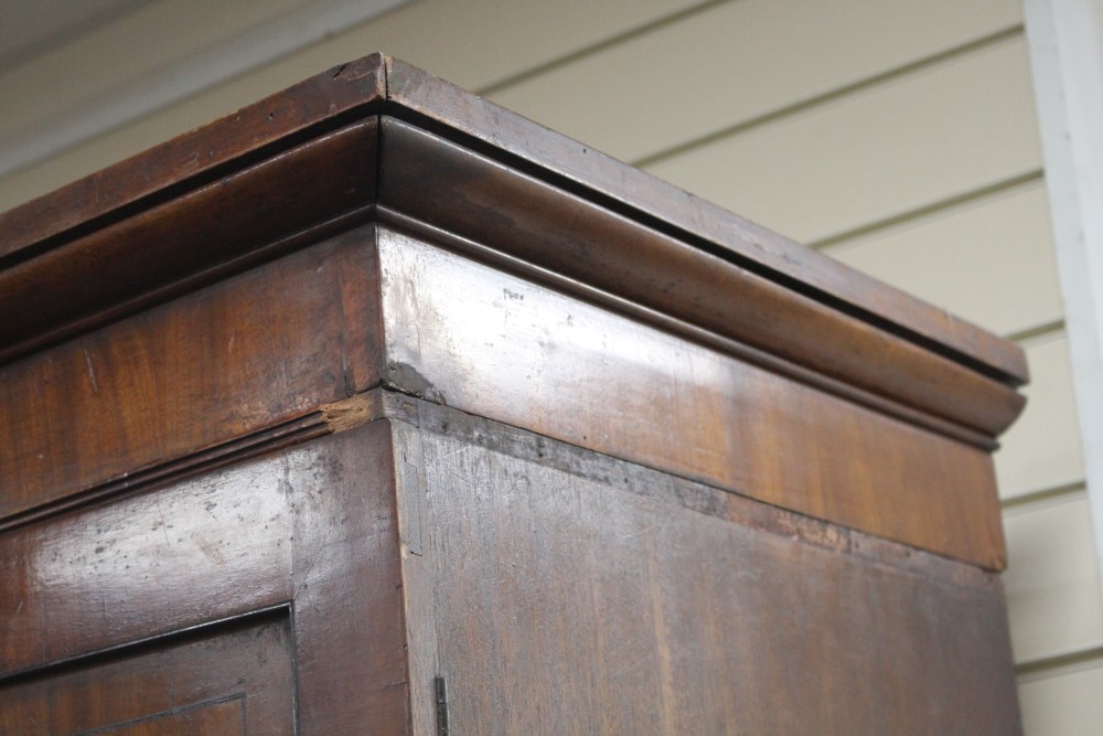 A Regency mahogany linen press with two doors enclosing five slides, two short drawers and two graduated long drawers, on swept bracket